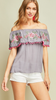 Grey Off-shoulder top featuring embroidery and pom-pom details